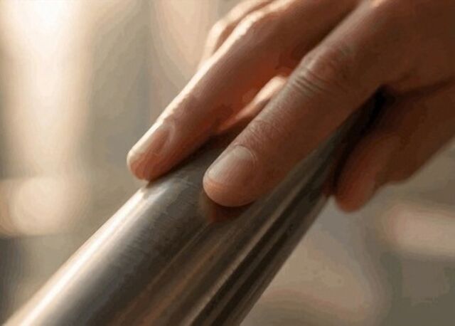 A hand resting on a bare steel handrail.